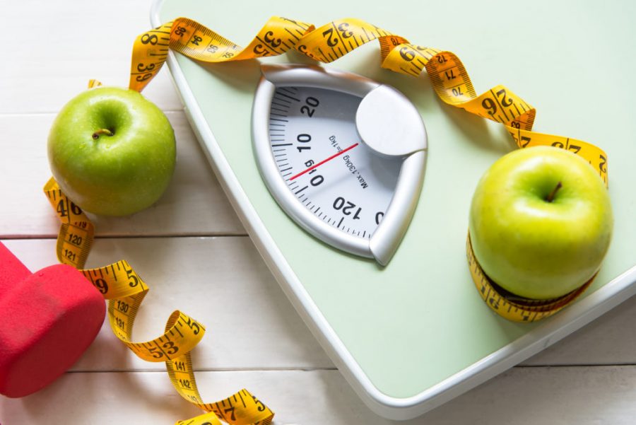 Green apple with weight scale and measuring tape for the healthy diet slimming . Diet and Healthy Concept